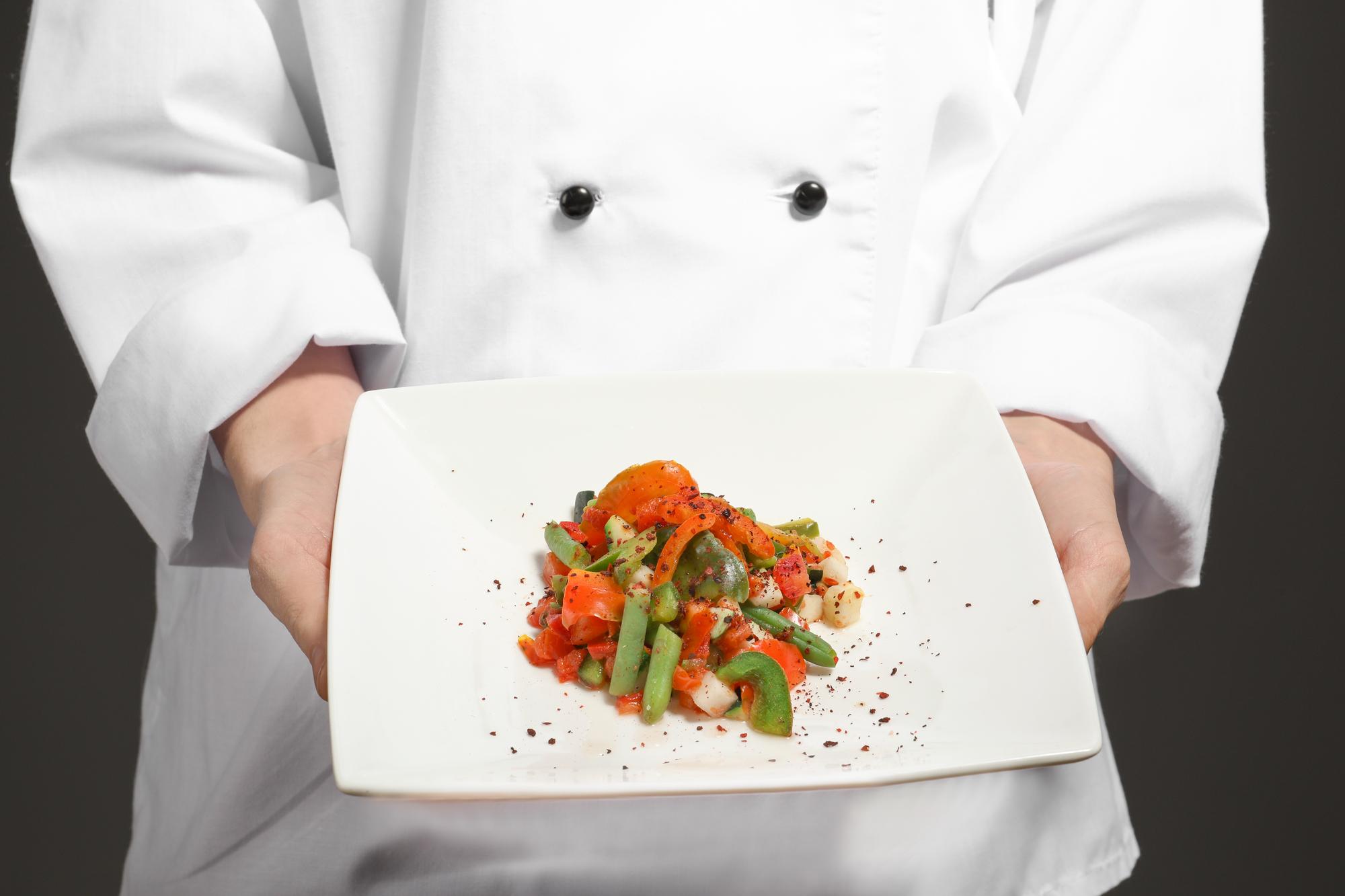Chef presenting plated dish in a studio kitchen
